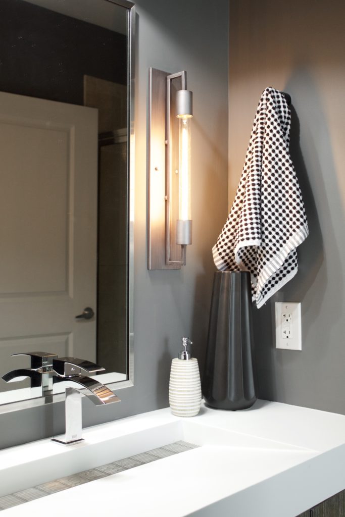 Our Encore Condo project features a modern masculine owner's bathroom with a wall-mounted double floating vanity and 4" thick integrated matte white trough sink against dark gray walls. #modernmasculine #ownersbathroom #condobathrooms #BehrAsphaltGray