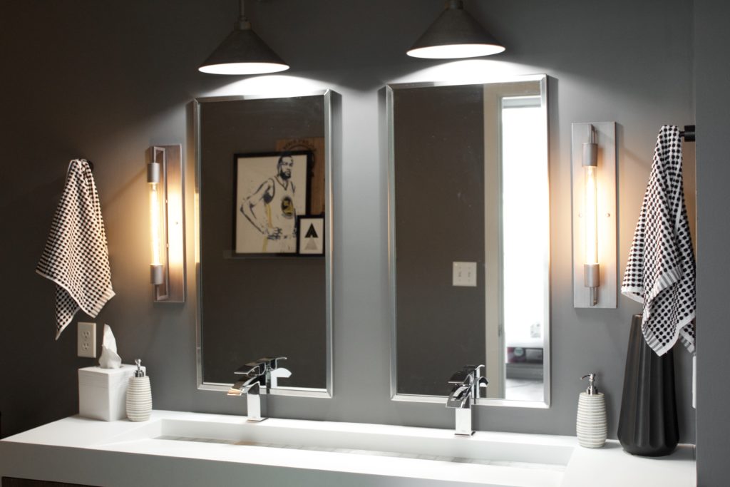 Our Encore Condo project features a modern masculine owner's bathroom with a wall-mounted double floating vanity and 4" thick integrated matte white trough sink against dark gray walls. #modernmasculine #ownersbathroom #condobathrooms #BehrAsphaltGray