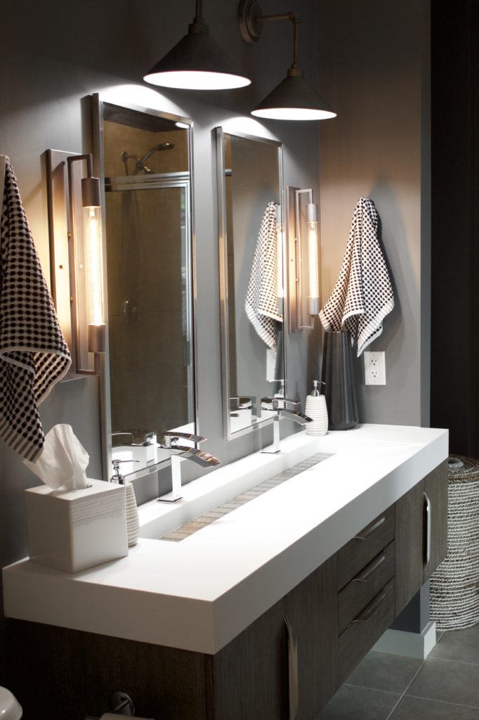 Our Encore Condo project features a modern masculine owner's bathroom with a wall-mounted double floating vanity and 4" thick integrated matte white trough sink against dark gray walls. #modernmasculine #ownersbathroom #condobathrooms #BehrAsphaltGray