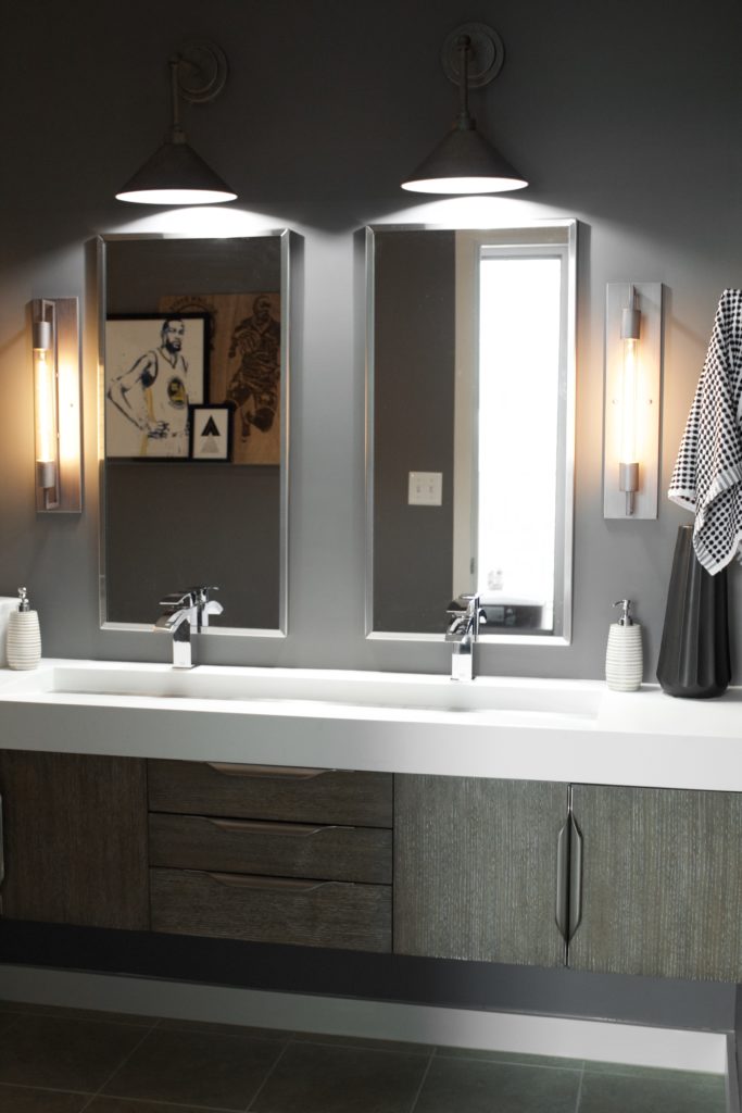 Our Encore Condo project features a modern masculine owner's bathroom with a wall-mounted double floating vanity and 4" thick integrated matte white trough sink against dark gray walls. #modernmasculine #ownersbathroom #condobathrooms #BehrAsphaltGray