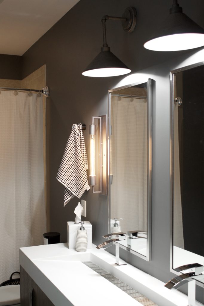 Our Encore Condo project features a modern masculine owner's bathroom with a wall-mounted double floating vanity and 4" thick integrated matte white trough sink against dark gray walls. #modernmasculine #ownersbathroom #condobathrooms #BehrAsphaltGray