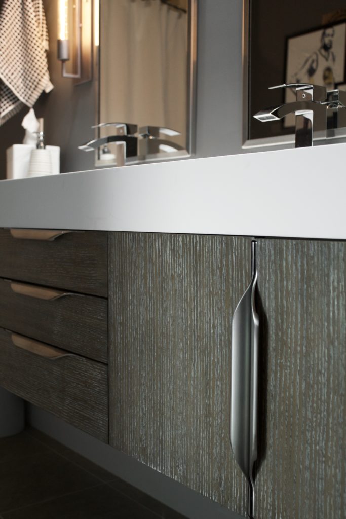 Our Encore Condo project features a modern masculine owner's bathroom with a wall-mounted double floating vanity and 4" thick integrated matte white trough sink against dark gray walls. #modernmasculine #ownersbathroom #condobathrooms #BehrAsphaltGray