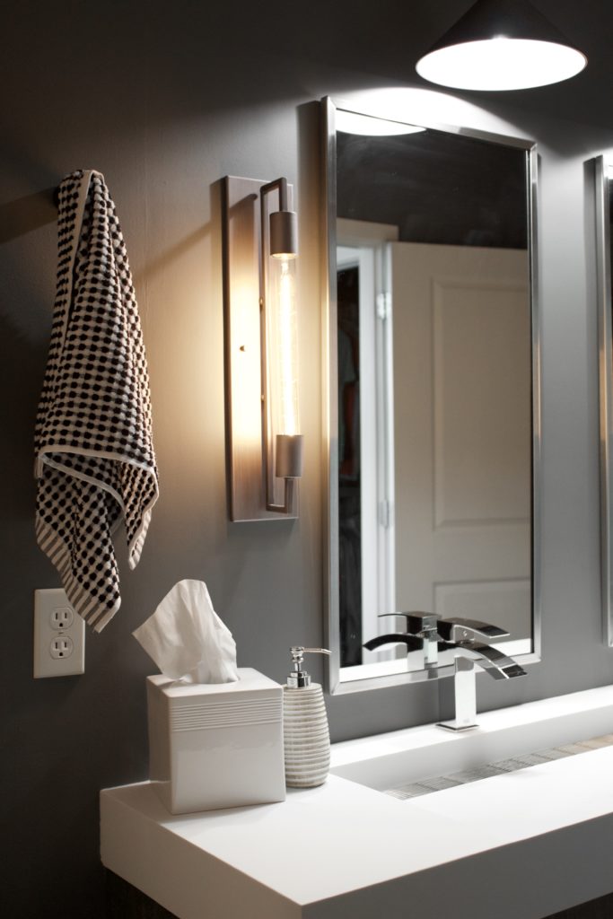 Our Encore Condo project features a modern masculine owner's bathroom with a wall-mounted double floating vanity and 4" thick integrated matte white trough sink against dark gray walls. #modernmasculine #ownersbathroom #condobathrooms #BehrAsphaltGray