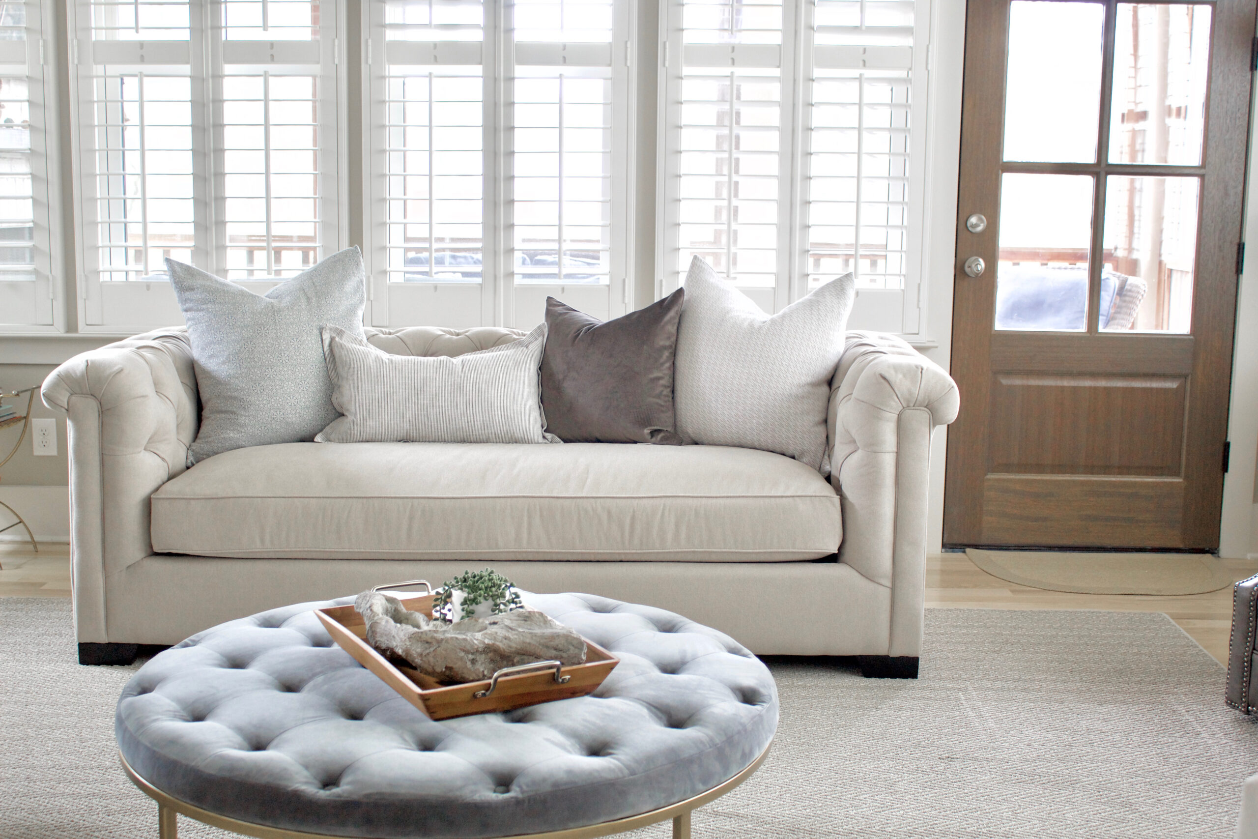 A light gray tufted sofa with traditional influence and modern flare. As part of the Kelly Clarkson Home Collection, it features a tufted back with matching roll arms and a bench-style cushion. The velour upholstery adds a welcoming, luxe element that makes it perfect for a contemporary living space. #lightgraysofa #lightgraytuftedsofa #tuftedsofa #contemporarytuftedsofa #benchseatsofa #KellyClarksonHomeCollection
