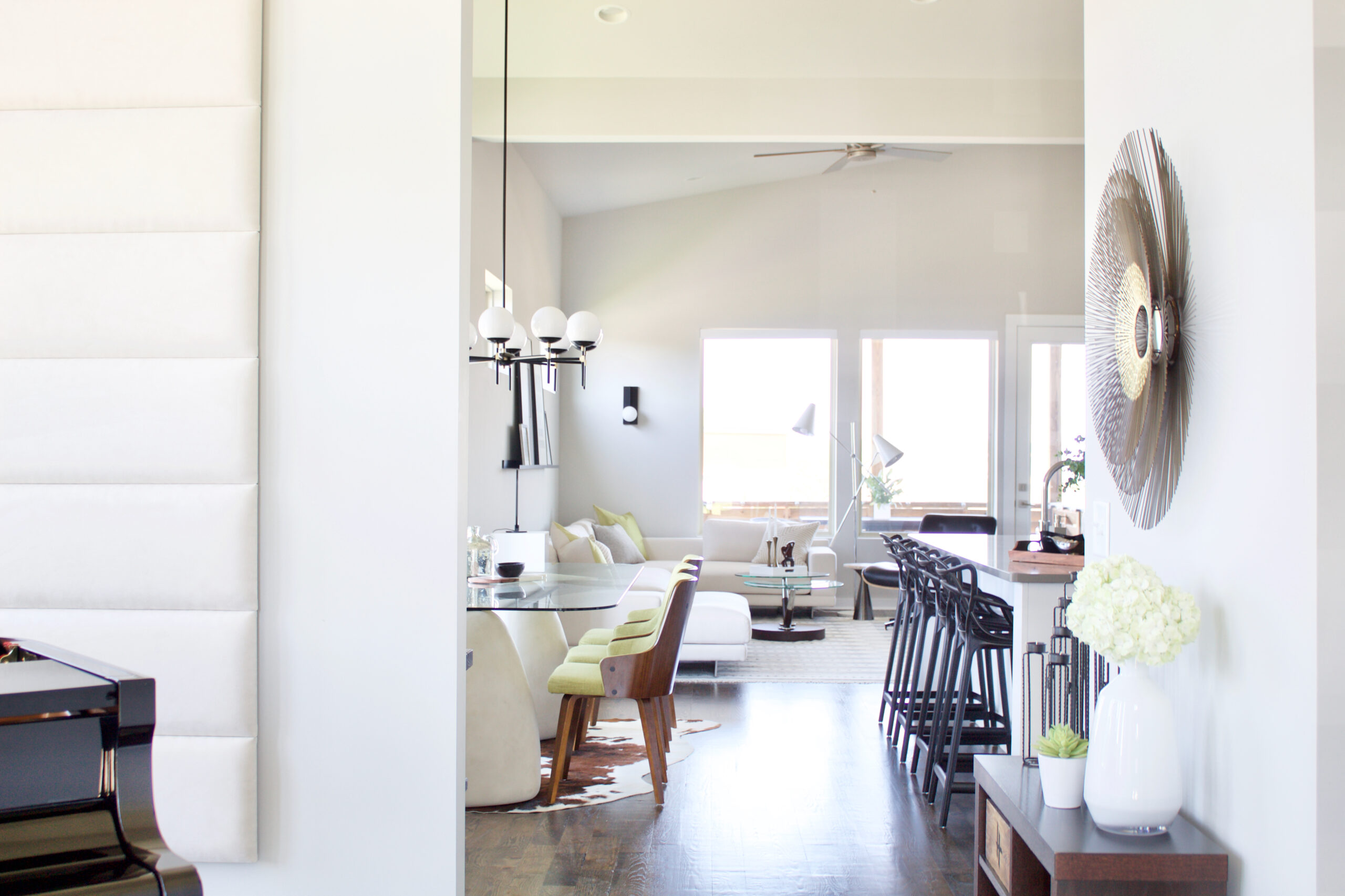 The foyer of our #MinimalModernSouthNashville project features modern entry lighting suspended over a baby grand piano with large windows on three walls and a sloped ceiling that reaches 15'H. The spherical pendant is made of white bands that diffuse the light and create a soft, dimensional glow. Light is also projected directly upward and downward to dramatically highlight the space, making it the perfect welcoming statement piece. Interior wall and ceiling color is Sherwin Williams Repose Gray SW 7015. The trim is bright white. #SherwinWilliamsReposeGrayInteriorWalls #ReposeGraySW7015 #interiorpaintcolor #lightgrayinteriorpaintcolors