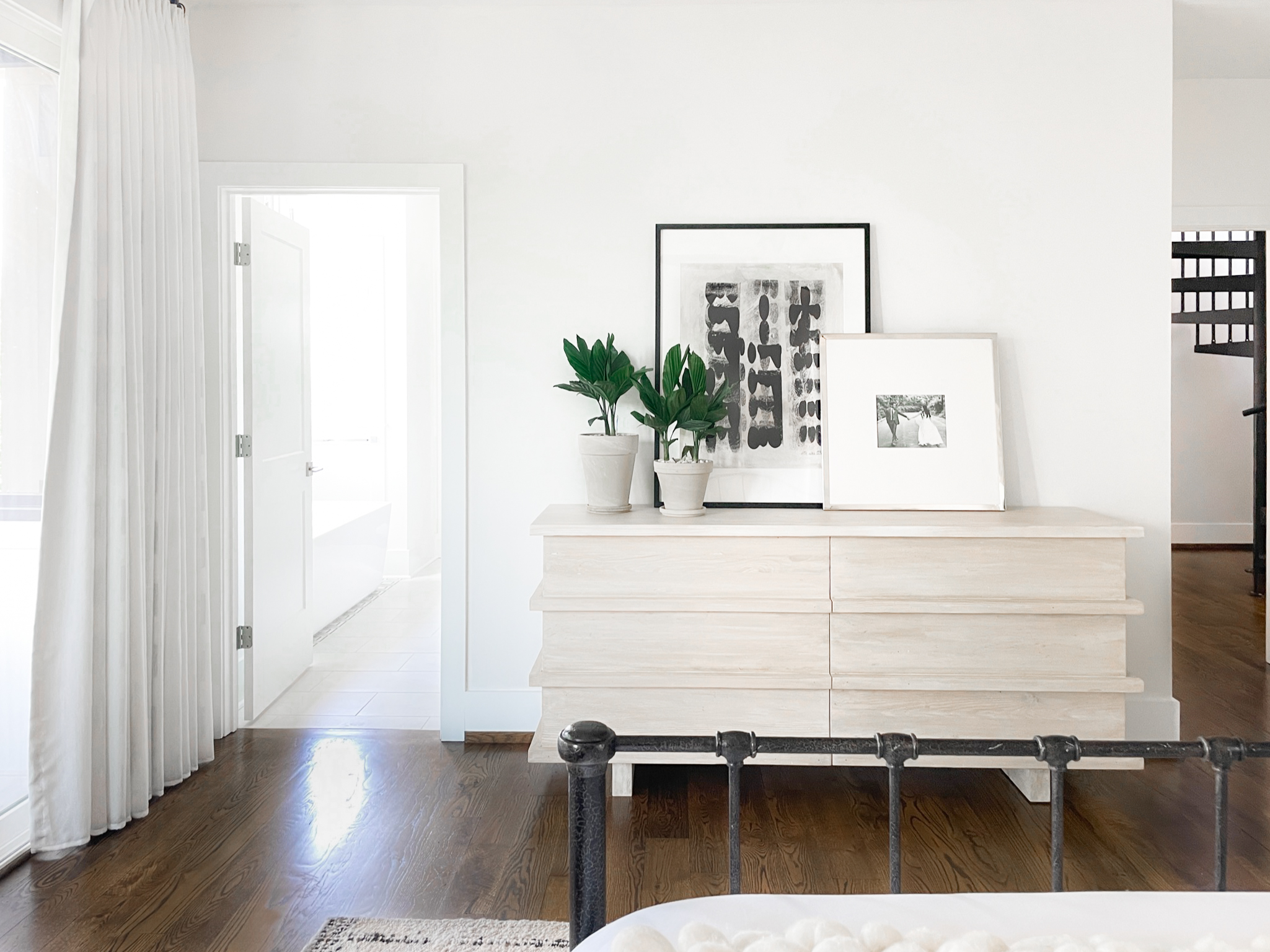 White Bridge Owner’s Bedroom and Porch. West Nashville, Tennessee. Featuring warm wood tones and creamy accents against white walls and dark wood floors.